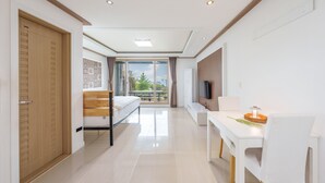 Habitació d'hotel moderna amb llit, escriptori, televisió i balcó amb vistes.