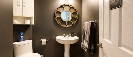 A bathroom with a toilet, sink, and a mirror with a gold frame.
