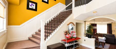 A multi-level home interior with a staircase, a dining area, and a living room.