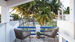 Ein Balkon mit zwei Korbstühlen, einem Blumentopf und einem gemusterten Boden.