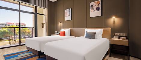 A modern hotel room with two beds, a large window with a view, and a small bedside table with a lamp.