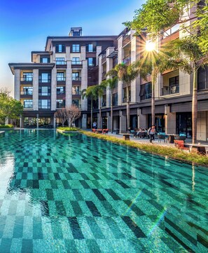 A modern hotel with a large outdoor swimming pool, multiple balconies, and outdoor seating areas. - Lujiang Mega Hotel (Xiamen)