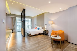 Habitación de hotel moderna con una cama grande, un escritorio y una silla. Hay un televisor y una lámpara sobre el escritorio.