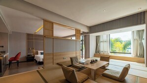 Una habitación de hotel moderna con esteras de tatami, un área de comedor y vistas a la vegetación.