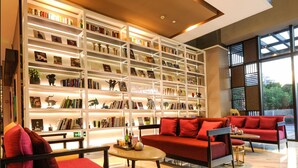 Una biblioteca moderna con estanterías múltiples, un sofá rojo y una mesa de centro.