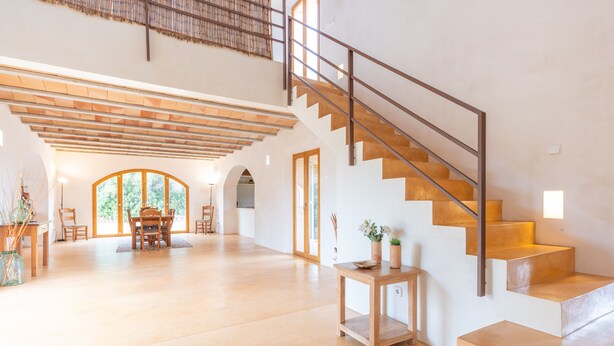 Ein geräumiger Wohnbereich mit Treppe, einem Esstisch und einem kleinen Tisch mit Pflanzen.