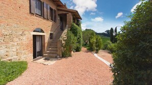 A rustic stone building with a brick facade, a wooden staircase leading to a covered porch, and a gravel pathway. - Villa La Cascata with swimming pool (Chiusi)