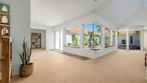A spacious, modern interior with large windows, a wooden floor, and a view of the outdoors. - Colonial Modern Villa Sleep 14-Pool, Palapa, Court (Noord)