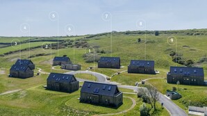 An aerial view of a rural property with multiple buildings numbered 1-9, surrounded by green fields and a clear sky. - 6 The Vista - Hot tub/ Pet friendly/ On-site pool/ EV Charger/ Ecohome (Woolacombe)