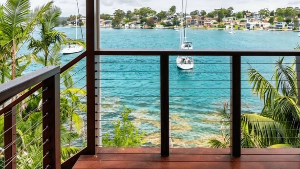 A balcony with a view of a marina and a town across the water.