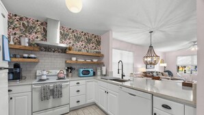 A modern kitchen with white cabinets, a microwave, a kettle, and a sink. - Updated! Beautiful Decor! Walk to Beach & Eats (St. Augustine)