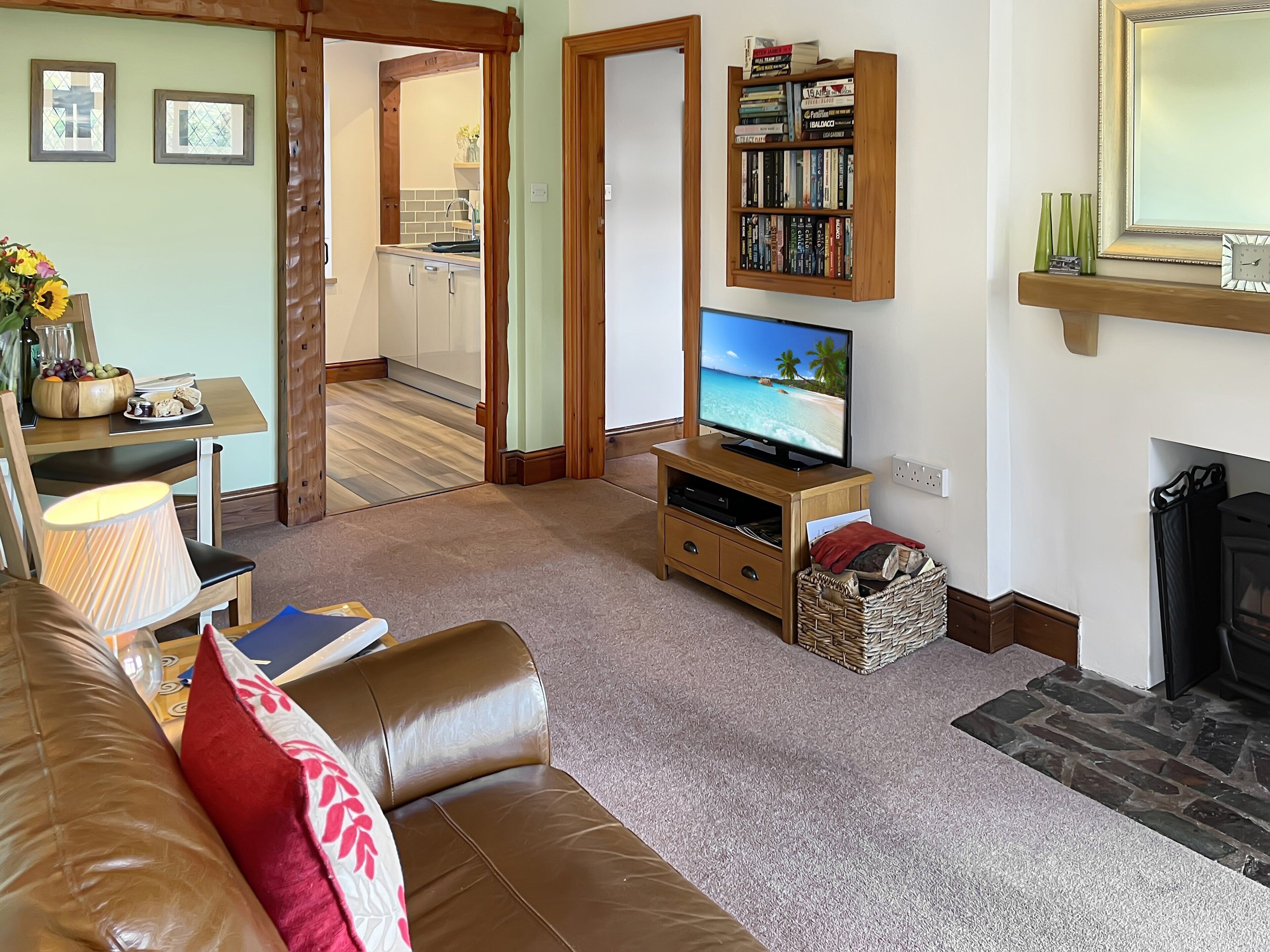 Een woonkamer met een leren bank, een televisie, een boekenkast en een open haard.