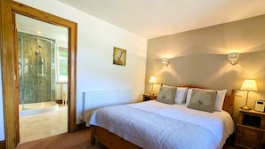 Een slaapkamer met een houten bed, twee bedlampen, een radiator en een douchecabine van glas.