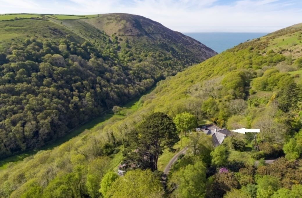 Paesaggio collinare con una casa immersa nel verde.