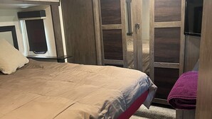 Ein Schlafzimmer mit Bett, Kleiderschrank und Fernseher.