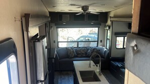 Ein kompaktes Wohnmobil-Interieur mit Küchenzeile, einer Sitzecke und einem Deckenventilator.