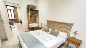 A neatly arranged bedroom with a large bed, a wooden wardrobe, a bedside table with a lamp, and a chair in the corner. - VLC HOST - Alfaro A (Valencia)