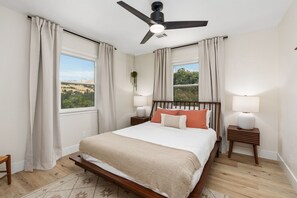 A bedroom with a bed, two bedside tables with lamps, a ceiling fan, and a view of the outdoors. - Stunning Sequoia Hills Villa w/ pool, Game room, Hot tub, Firepit and EV charger (Three Rivers)