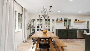 A modern kitchen with a wooden dining table, green cabinets, and a chandelier. - Stunning Sequoia Hills Villa w/ pool, Game room, Hot tub, Firepit and EV charger (Three Rivers)