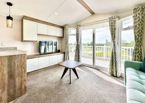 Eine moderne Küche mit Fernseher, Holzschränken, einem Esstisch und einem Balkon mit Vorhängen.