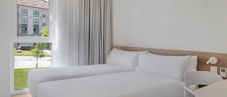 Una habitación de hotel con una cama grande, vistas a un edificio y una ventana con cortinas.