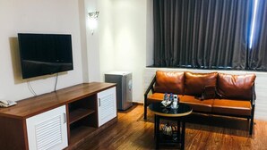 A modern living room with a wooden entertainment unit, a flat-screen TV, a leather sofa, and a coffee table. - Hoang Gia Hotel 150 Nghi Tam HN-BayLux (Hanoi)