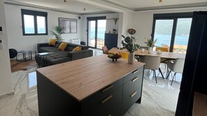 A modern kitchen with a central island, a dining area with a view, and a living space with a sofa and a coffee table.