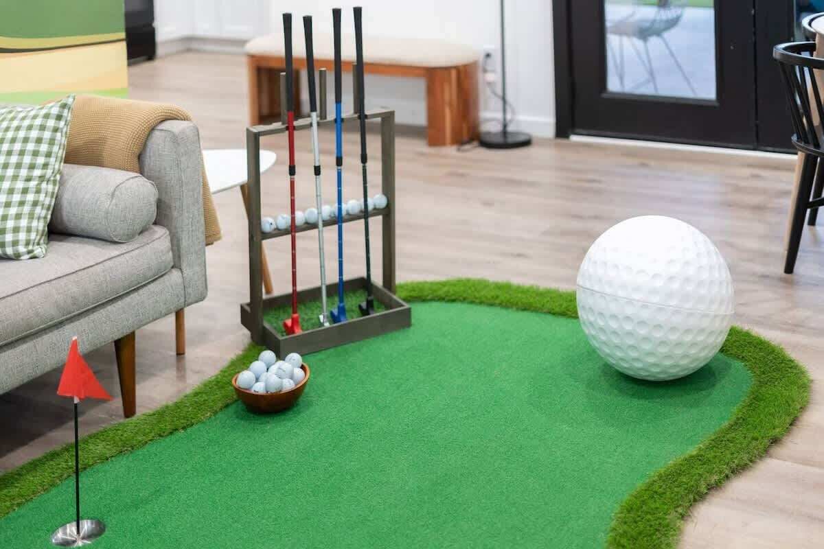 Un campo da minigolf con erba sintetica verde, una pallina da golf e un portabigliotti da golf.