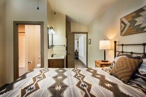 A bedroom with a bed, bedside table, lamp, and a mirror. - Yosemite's Meadow Haven (Yosemite National Park)
