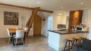 Una cocina moderna con una isla central, taburetes de bar y un comedor con mesa y sillas de madera.
