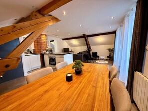 A dining area with a wooden table, chairs, and a potted plant. - *2 rooms SUPERB LAKE VIEW 5mn Evian (Lugrin)