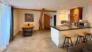 Una cocina moderna con una isla central, taburetes de bar y un comedor con mesa y sillas.