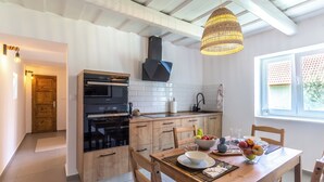 Een moderne keuken met houten kastjes, een zwarte oven en een hangende lamp.