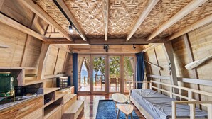Een houten interieur met een videbed, ingebouwde planken en een uitzicht door grote glazen deuren.