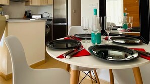 Cocina moderna con armarios de madera, un refrigerador de acero inoxidable y un comedor con una mesa redonda para dos.