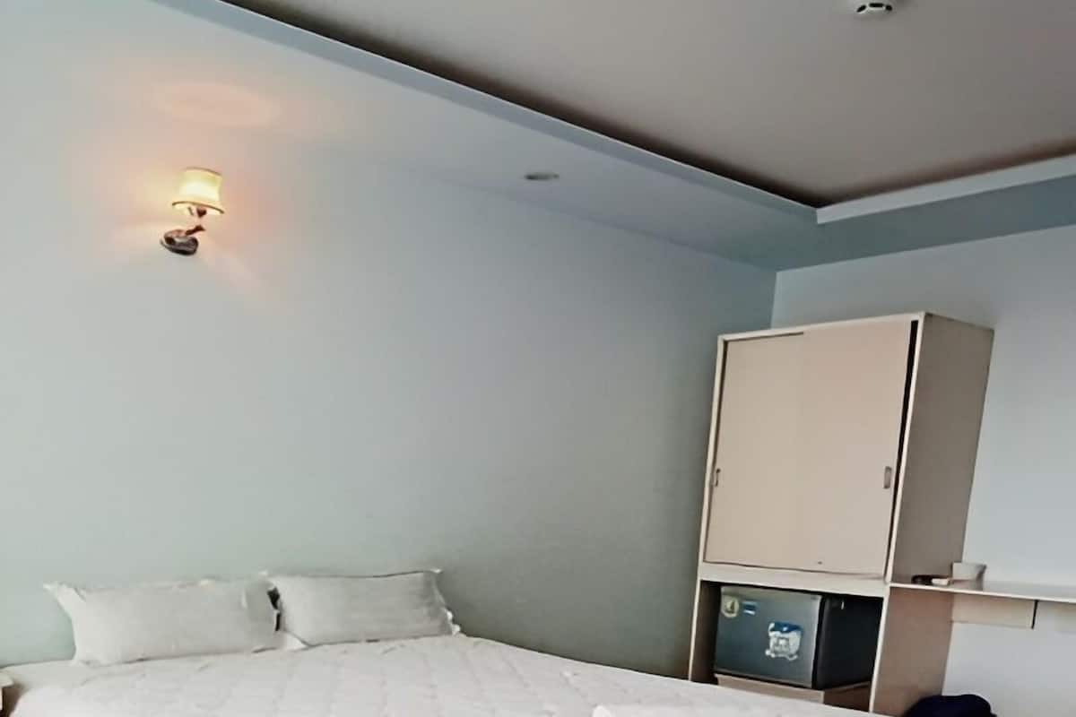 A bedroom with a large bed, a wardrobe, and a wall-mounted light fixture.