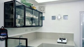 A compact kitchen with a built-in cabinet displaying dishes, a sink, and a gas stove.