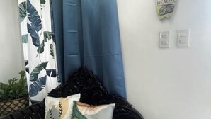 A room with a black leather sofa, a blue shower curtain, and a wall-mounted sign.