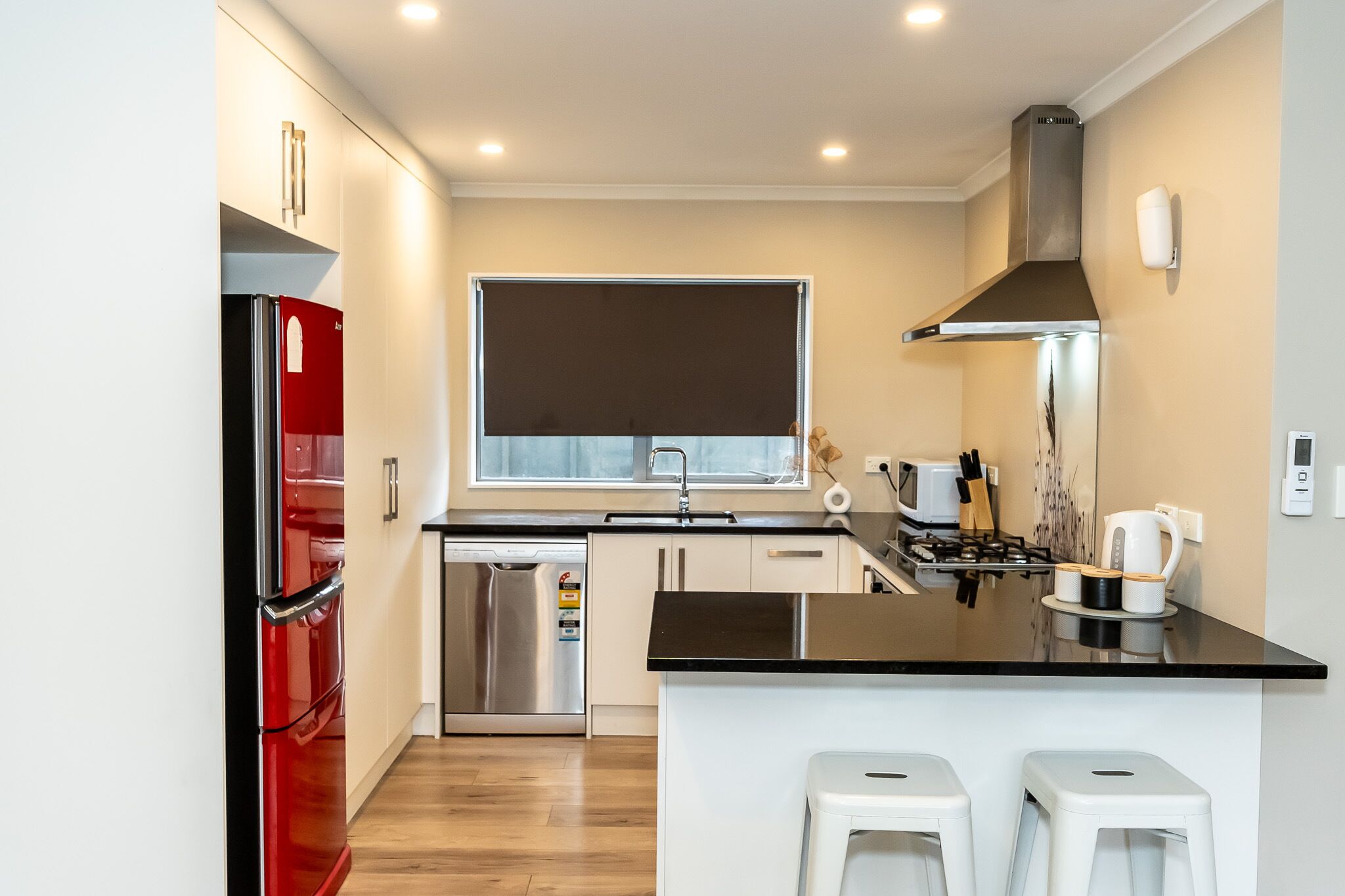 A modern kitchen with a stainless steel refrigerator, a dishwasher, a stove, and a window above the sink.