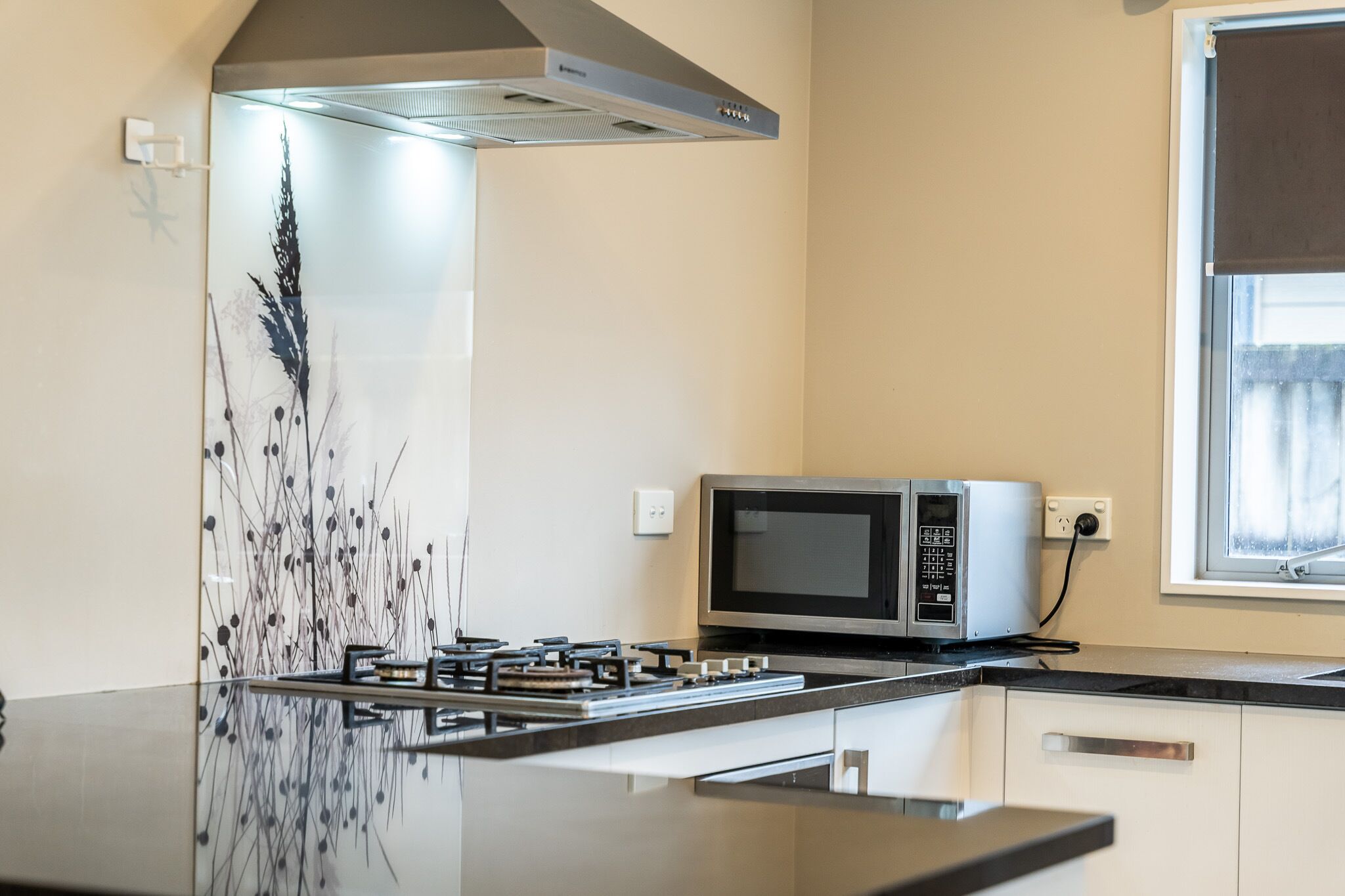 Una cocina moderna con estufa a gas, microondas y un panel decorativo en la pared.