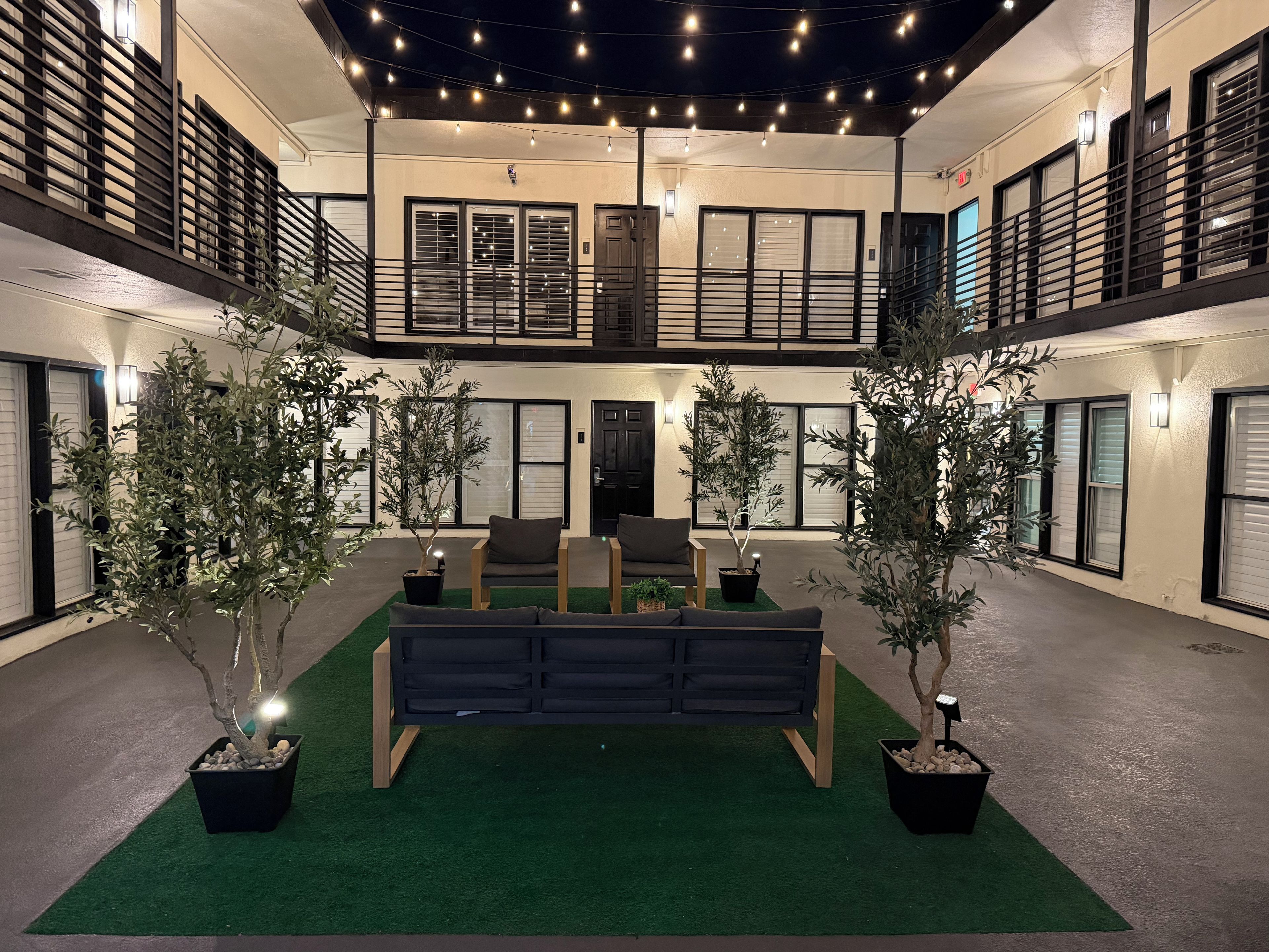 A spacious atrium with a central seating area, surrounded by potted plants and a balcony with railings.