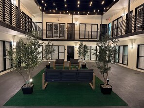 Un vaste atrium doté d’un espace de repos central, entouré de plantes en pot et agrémenté d’un balcon avec des balustrades.