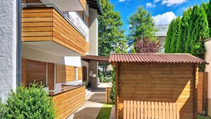A modern building with a wooden facade, a visible sign reading 'Haus Birkenhain,' and a small wooden structure in the foreground. - Am Birkenhain by Interhome (Seefeld in Tirol)