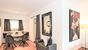 A modern living room with a dining area, a grey sofa, a dining table with chairs, a large mirror, and a painting on the wall. - Am Birkenhain by Interhome (Seefeld in Tirol)
