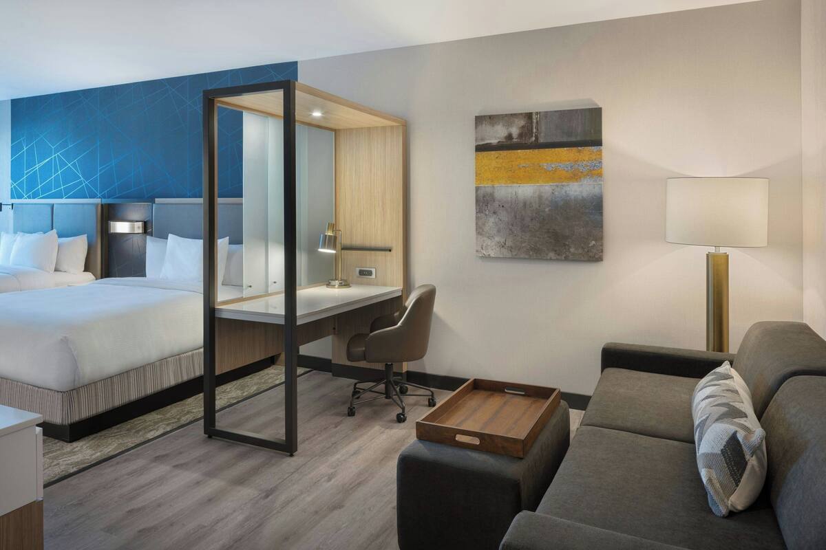 A hotel room with a bed, desk, chair, and a sofa.