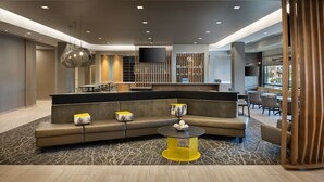 A modern lobby with a sectional sofa, a round table, and a TV mounted on the wall. - SpringHill Suites by Marriott Bowling Green (Bowling Green)
