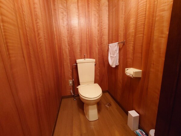 A small, wooden-paneled bathroom with a toilet, a towel rack, and a toilet paper holder. - Takayama stay Kakitsubata (Takayama)