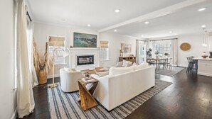 Un salon spacieux avec un canapé blanc, une cheminée et un coin repas comprenant une table et des chaises.