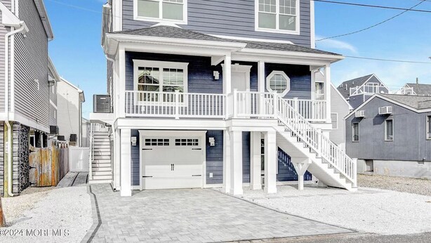 Une maison à deux étages avec un porche à l’avant, un garage et un escalier menant à l’étage supérieur.