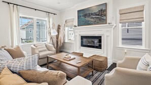 Un salon avec une cheminée, un tableau et une vue sur un bâtiment à l’extérieur.